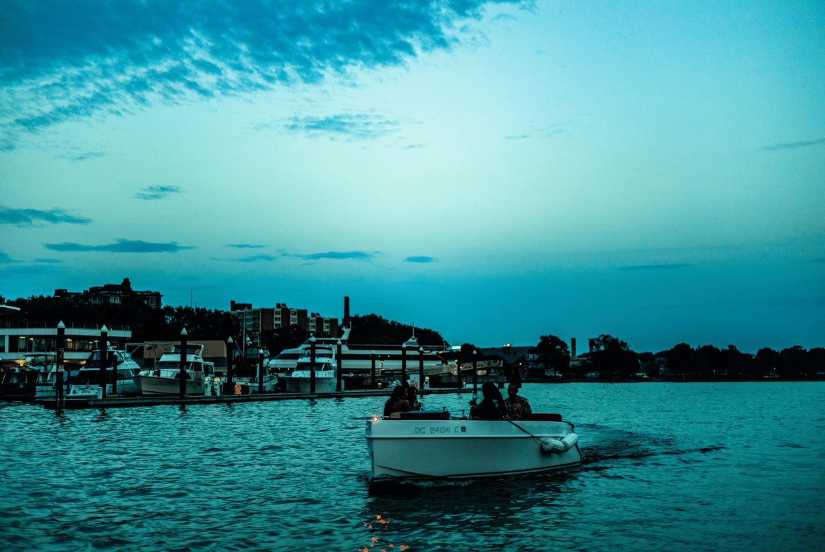 Guests cruising a Yachtsy boat past the marina at blue-hour dusk