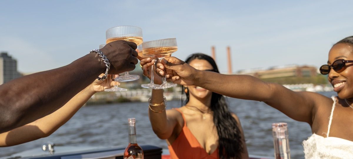 Friends toasting ros&eacute; over a charcuterie spread on a Yachtsy cruise