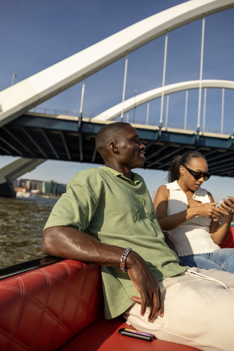 A couple relaxing on a Yachtsy picnic boat as it passes under a harbor bridge