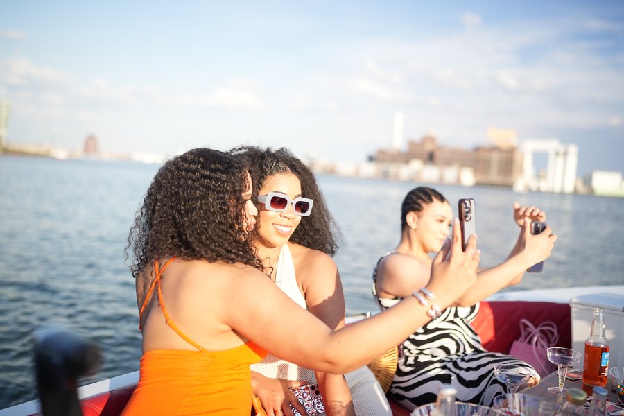 Friends hugging and taking photos at sunset on a private Yachtsy cruise