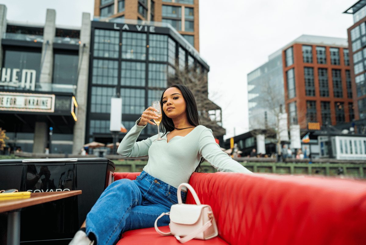 A guest sipping champagne on a Yachtsy boat with the DC Navy Yard waterfront behind