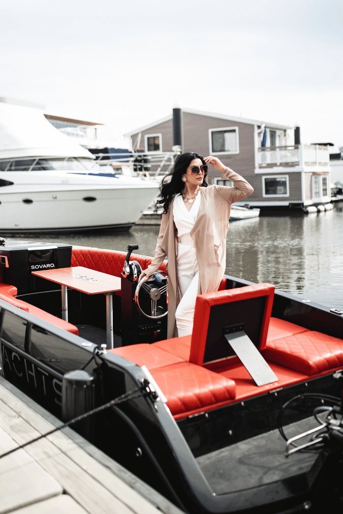 A guest at the helm of a docked Yachtsy boat beside the marina